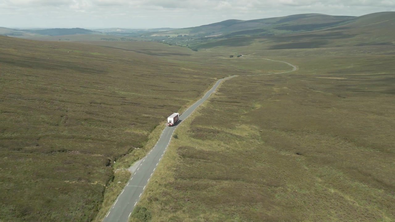 Caminhão a percorrer uma estrada estreita pelas cênicas Montanhas Wicklow na Irlanda em um dia nublado.