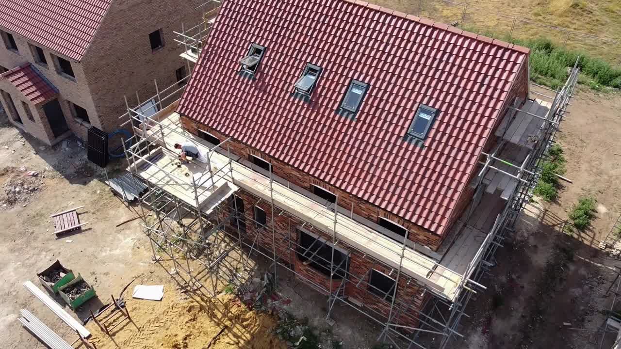 Vista aerea rotante di una casa di nuova costruzione impalcata e in costruzione, che mostra il prospetto frontale e il pignone