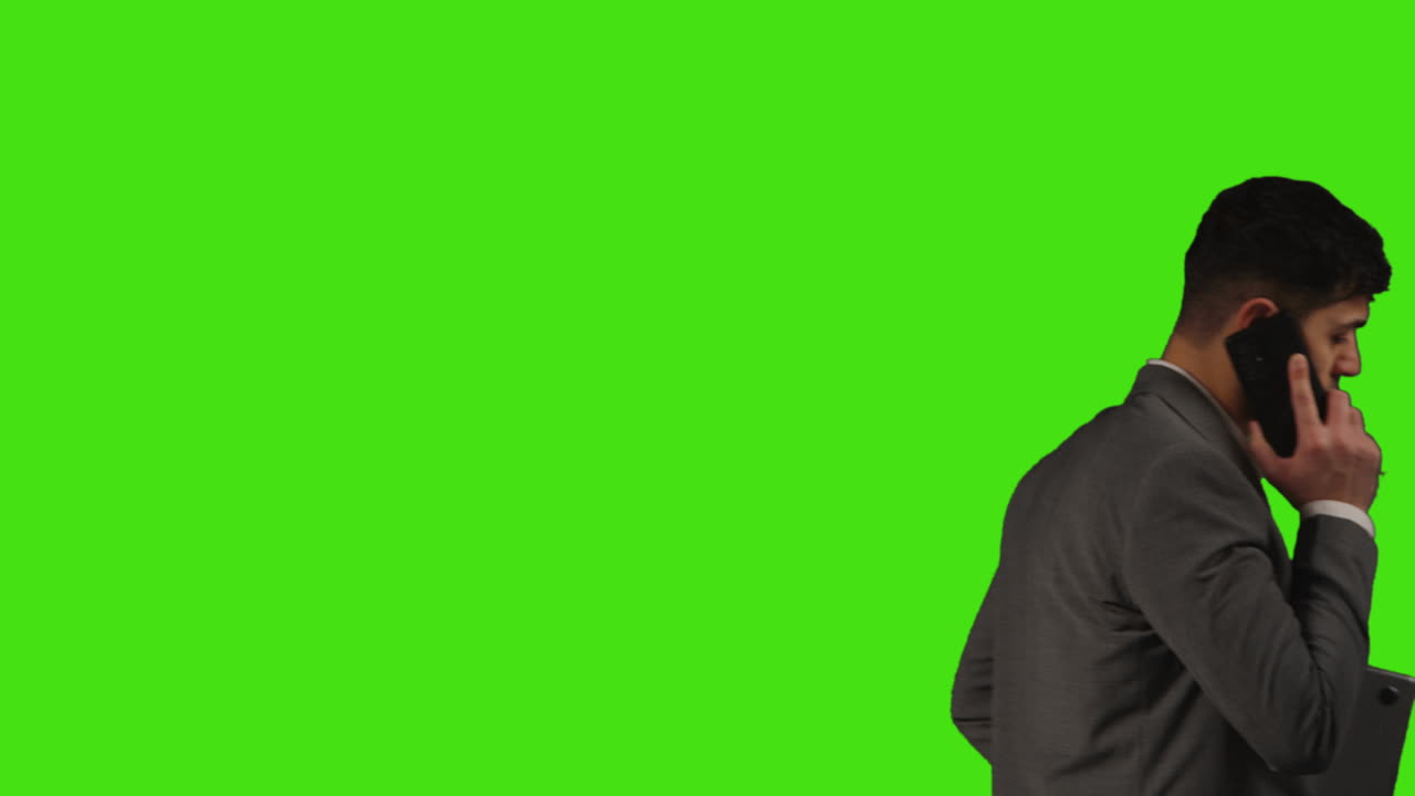 Close Up Of Businessman With Laptop Talking On Mobile Phone Walking Across Frame Against Green Screen Background 3