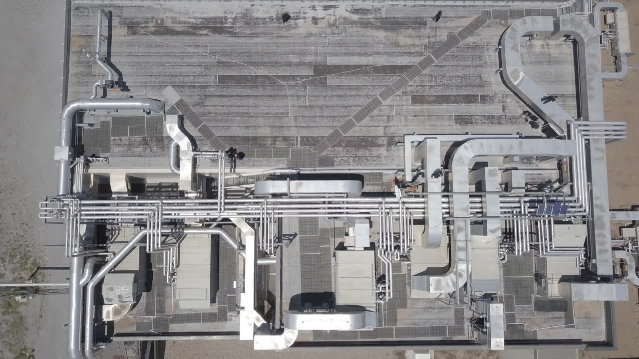Ripresa aerea dall'alto di un'enorme macchina di produzione moderna con un complesso sistema di tubazioni in un potente impianto di raffinazione di gas e petrolio in una giornata di sole