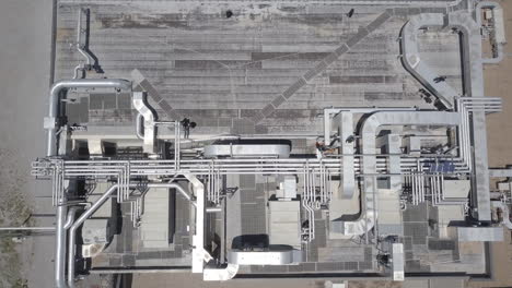 Aerial-top-down-shot-of-giant-modern-production-machine-with-complicated-pipeline-system-at-powerful-gas-and-oil-refinery-plant-on-sunny-day