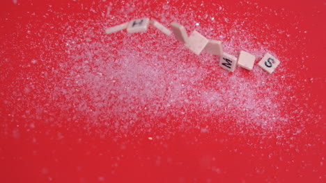 white letter tiles moving to spell out christmas on glitter