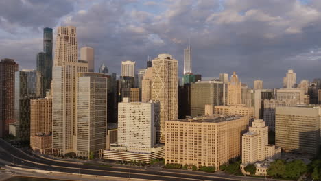 aerial footage in the light of the golden sunrise flying away from downtown chicago, illinois