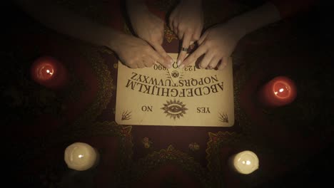 ouija board with hands and candles