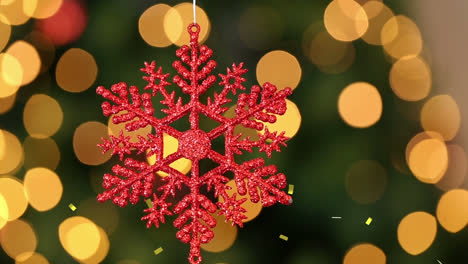 Animation-of-gold-confetti-falling-over-red-snowflake-christmas-tree-decoration,-with-bokeh-lights