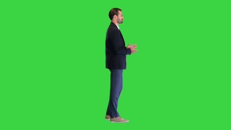 happy young businessman standing and applauding on a green screen, chroma key