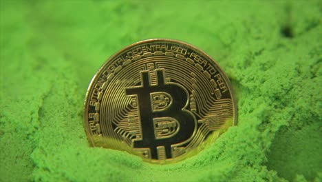 moneda de oro bitcoin en un mar de verde con destellos de luz y reflejos