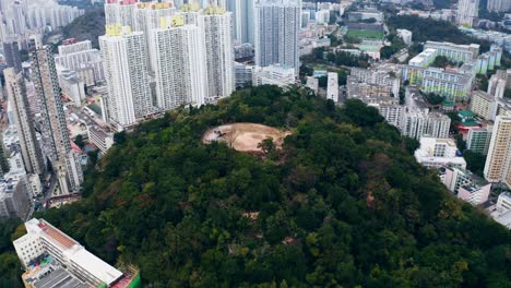 Vista-De-Drones-De-Una-Colina-Llena-De-árboles-Y-Con-Un-Sitio-Histórico-En-La-Parte-Superior,-De-Pie-En-Medio-De-Una-Ciudad-Durante-El-Día