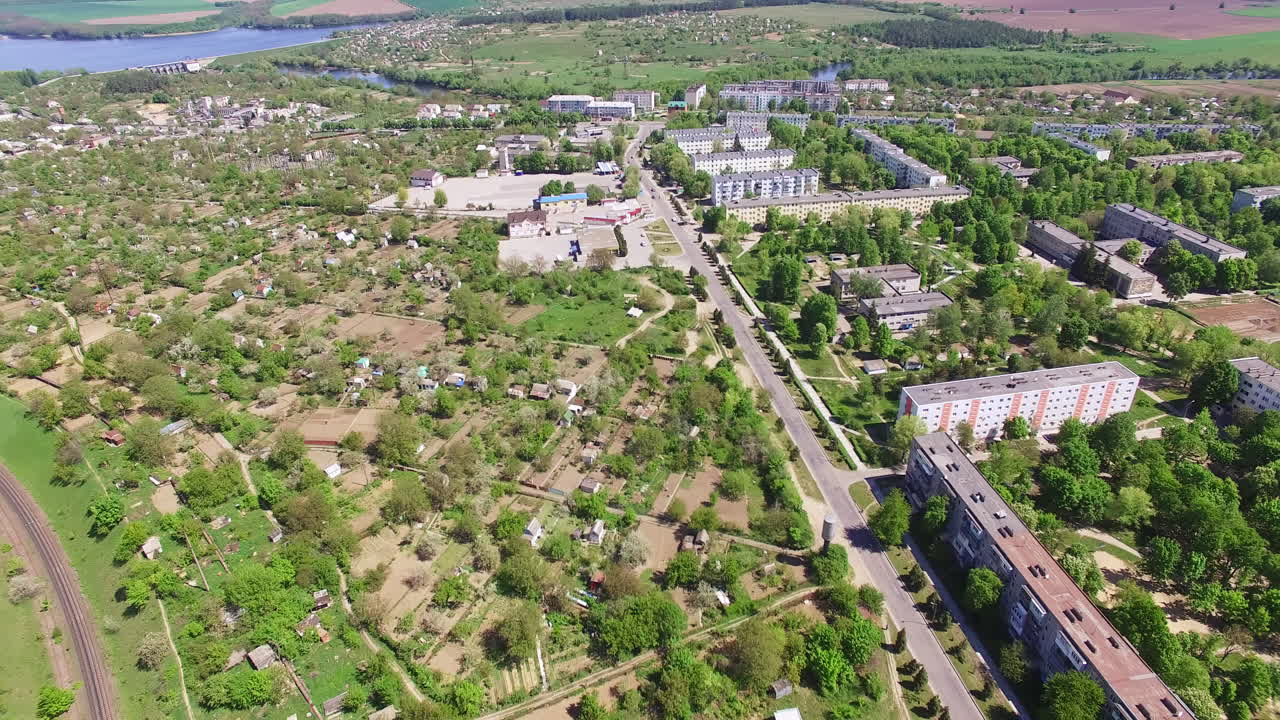City scenery on amazing sunny day. Green residential areas crossed by roads. Rural area and river at backdrop.