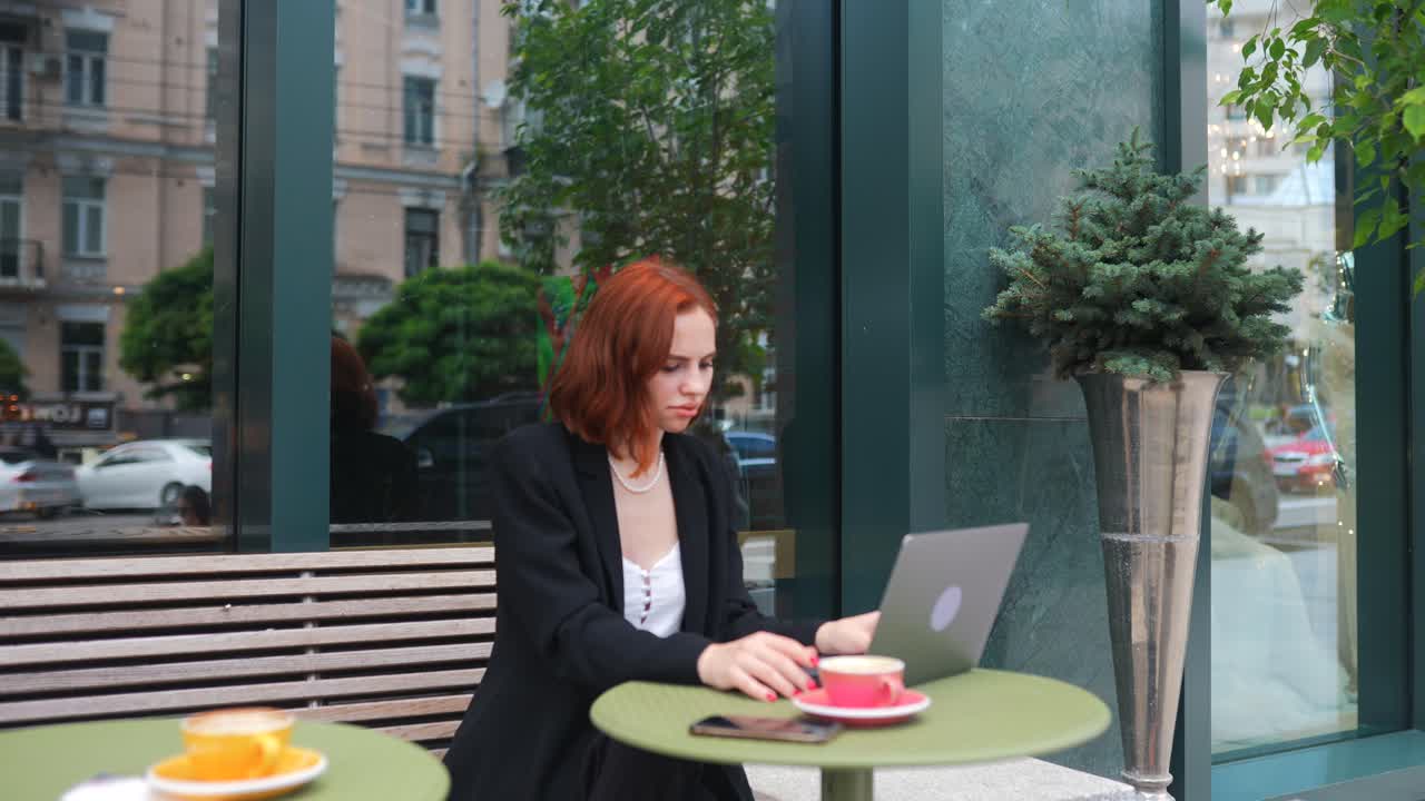 mujer trabajando en una computadora portátil en un café al aire libre