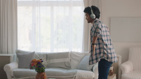 Un-Joven-Feliz-Bailando-En-Casa-Celebrando-El-éxito-Escuchando-Música-Usando-Audífonos-Divirtiéndose-Bailando-En-La-Sala-De-Estar-El-Fin-De-Semana