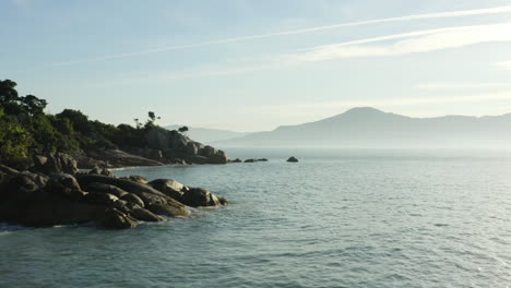 Vista-Aérea-De-Las-Olas-Del-Mar-Y-La-Puesta-De-Sol-Del-Océano-Una-Fantástica-Costa-Rocosa-Y-Neblina,-Jurere-Internacional,-Florianópolis,-Santa-Catarina,-Brasil