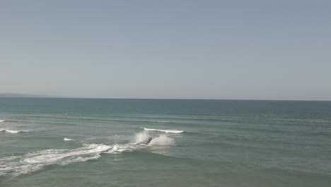 Jet-ski-riders-jump-over-ocean-surf-waves-at-Noosa-Heads-river-bar