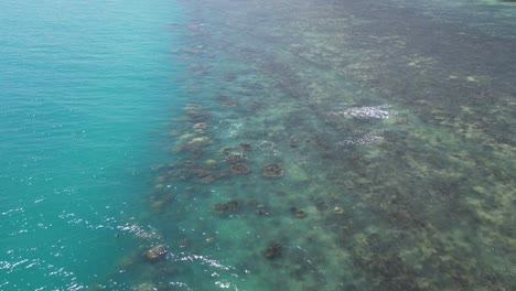 Slow-cinematic-drone-tilt-up-over-beautiful-coral-reef-to-beach-resort