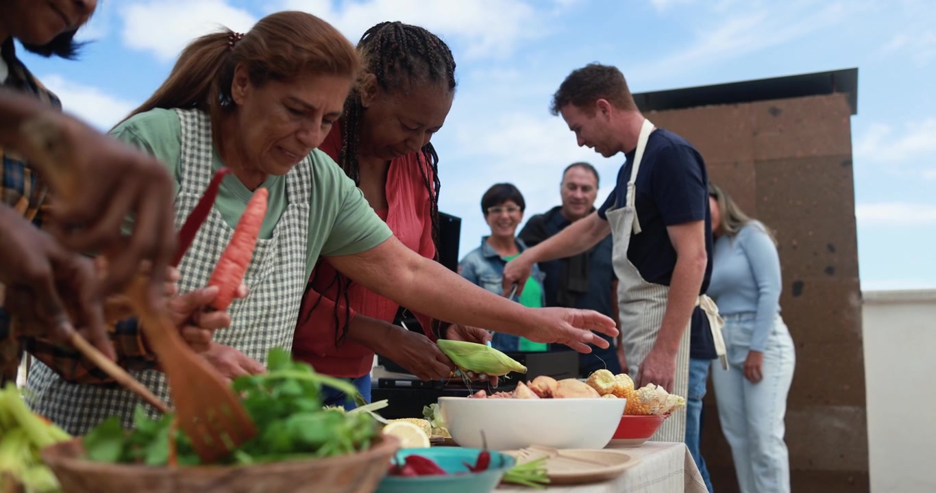 Venner af forskellige etniciteter forbereder mad til en grillfest på en tagterrasse