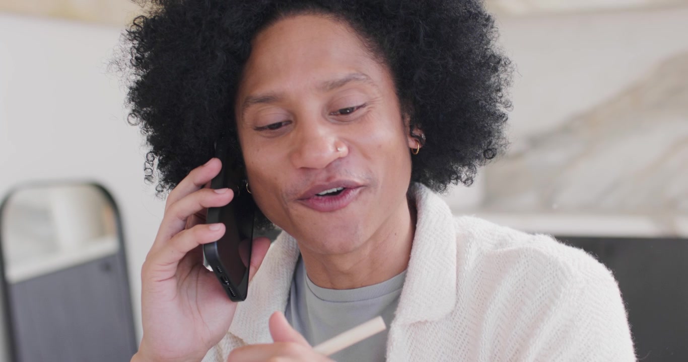 African American man answering ringing black cell while stirring stick and checking recipe kitchen