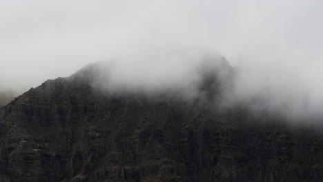 Dolly-Cinemática-Hacia-Los-Picos-De-Las-Montañas-Cubiertas-De-Nubes-En-El-Terreno-Accidentado-De-Fjallsárlón-Islandia