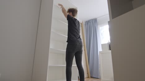 Carpenter-checks-quality-of-shelves,-static-wide