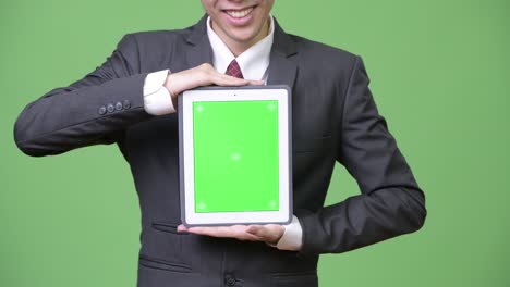 joven empresario asiático feliz mostrando la tableta digital a la cámara
