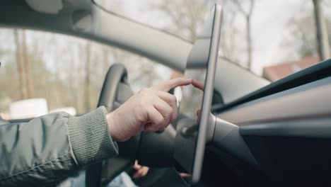 man typing on a touchscreen in an electric car