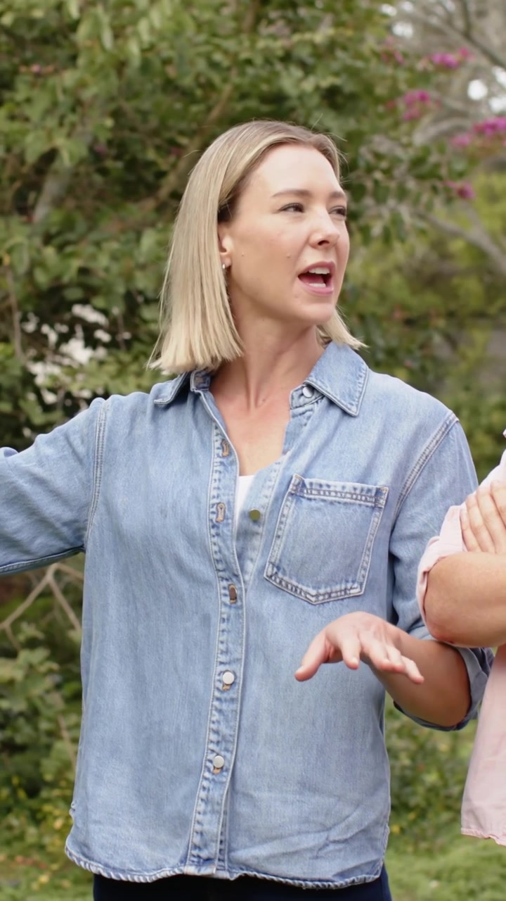 Video verticale: Voltandosi verso un amico, donna con smartwatch che parla in giardino, una persona in denim che indica il giardino.