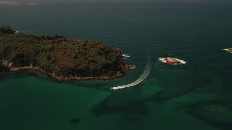 cinematic drone footage of speed boat racing around small secluded island