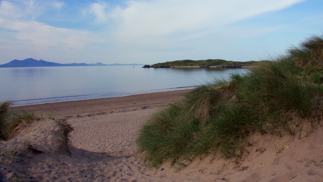 Wide shot in the dunes looking west over the beach and Ynys Llanddwyn island at Llanddwyn beach and at the Newborough National Nature Reserve
