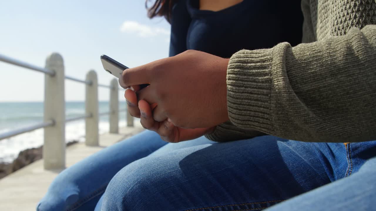 레일링 4k 근처의 산책로에서 휴대 전화를 사용하는 커플의 중간 섹션