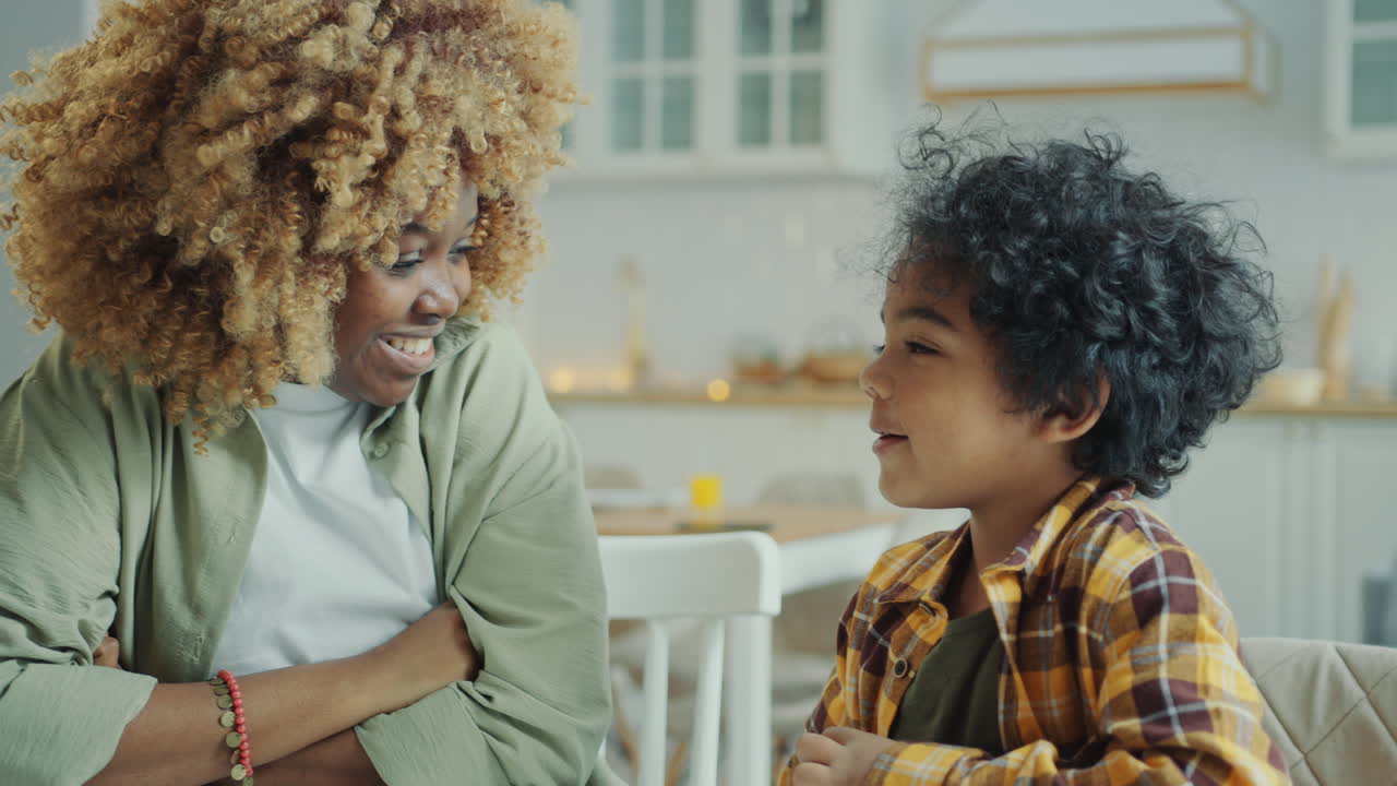 Madre afroamericana e figlioletto seduti a casa che conversano