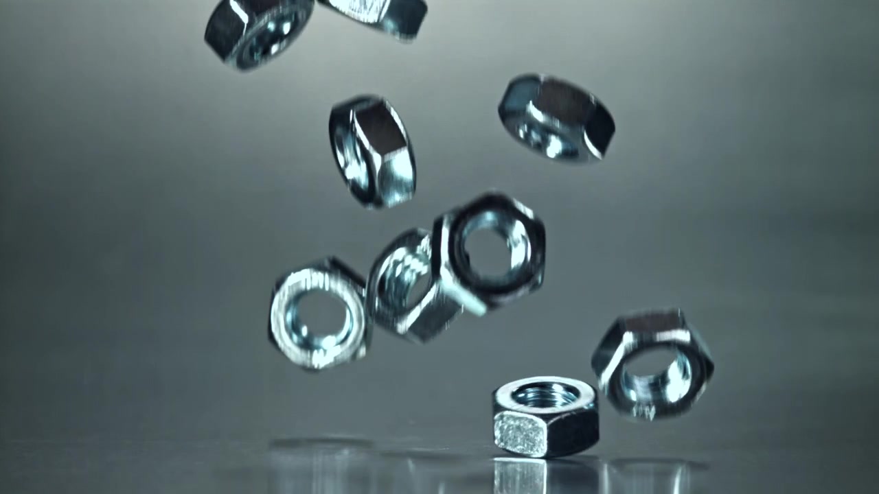 Shiny Metal Nuts Falling in Slow Motion on Grey Background