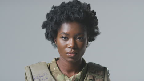 Studio-Portrait-Of-Serious-Young-Female-Soldier-In-Military-Uniform-Against-Plain-Background