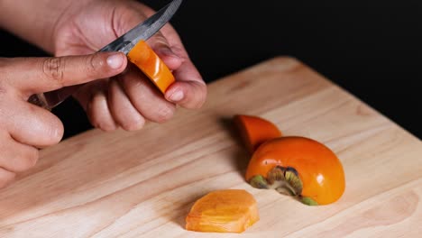 hands carefully slicing a ripe persimmon fruit