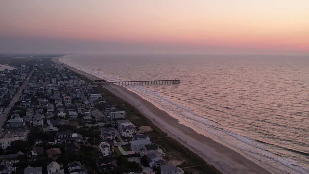Riprese aeree all'alba con molo per la pesca sullo sfondo, spiaggia di Wrightsville, Carolina del Nord