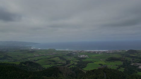 aerial view of the lush, green landscapes and rugged coastline of the azores, portugal, with rolling hills meeting the ocean under a dramatic sky. capturing the beauty of island's natural environment.