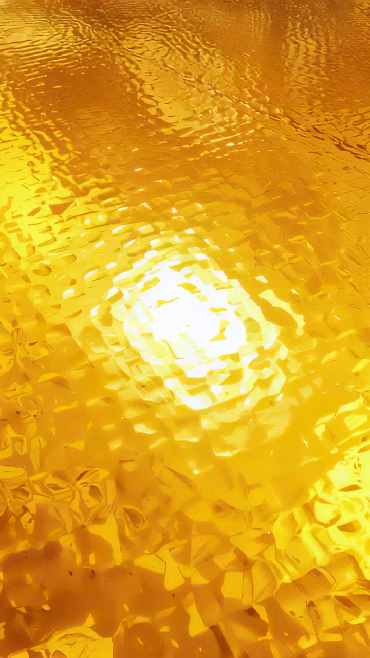 Vertical video: Moving camera shifting specular spot across textured gold foil macro revealing seam