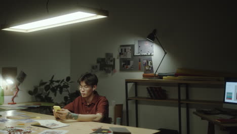 young person using a smartphone at a desk in a dimly lit office