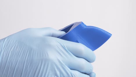 male wearing surgical gloves handling a 3d printed plastic mask during the covid-19 pandemic