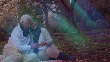senior couple holding hands on picnic blanket, overlaying animated health chart and heart icons