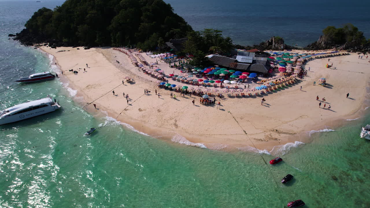 Aerial view of a tropical island beach with tourists and boats
