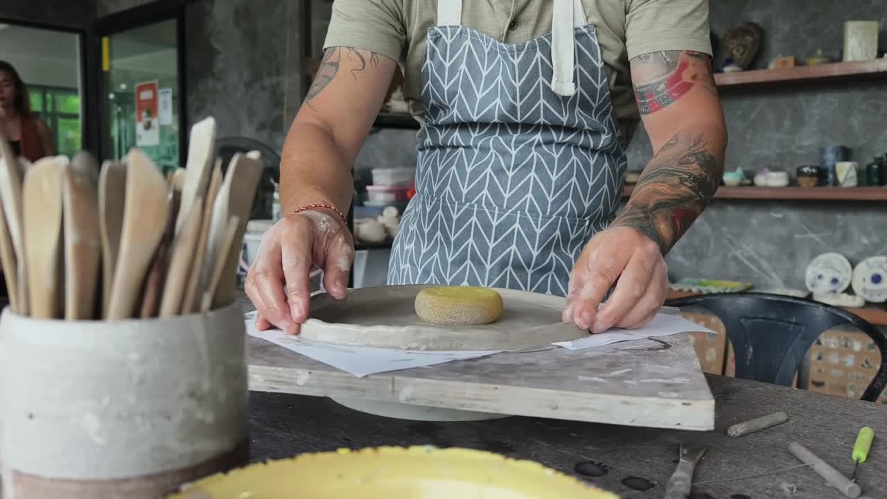 Artisan Shaping Clay Plate with Sponge in Pottery Workshop