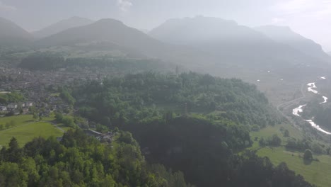 Aerial-view-of-Fiemme-Valley-surrounded-by-green-nature-and-silhouette-of-mountains-during-summer-day