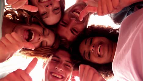 estudiantes felices de pie en círculo dando pulgares hacia la cámara