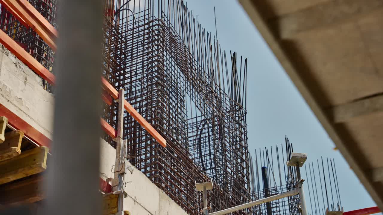Construction site. Dense steel rebar grid rises above a city construction site, framed by formwork and beams against a pale blue sky. structural skeleton before the concrete pour urban development,