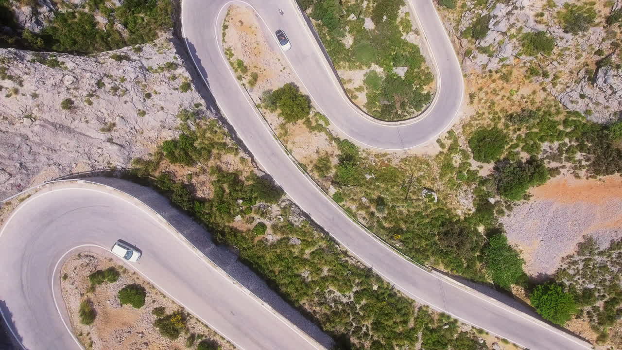 Vista aerea dall'alto verso il basso di strade di montagna tortuose con diversi veicoli sull'isola di Maiorca