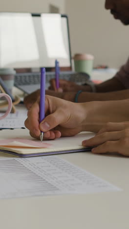 people writing notes in notebooks at a desk