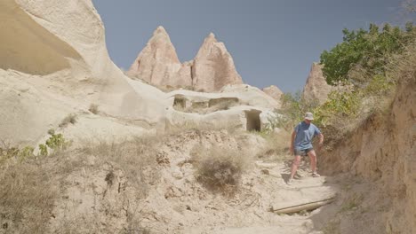 Woman-hiker-carefully-descends-steep-sandy-trail-path-rocky-landscape