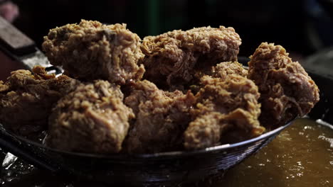 close-up of straining fried chicken after deep frying in a wok