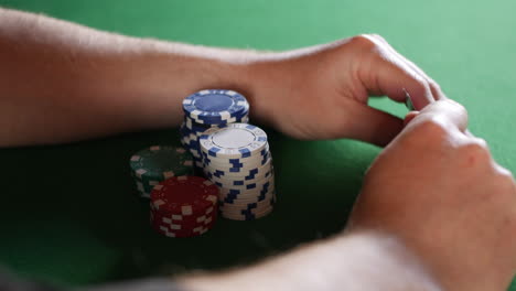 a man looking at his cards and guarding his poker chips