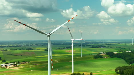 Aerial-highlighting-a-row-of-wind-turbines-standing-over-green-agricultural-fields