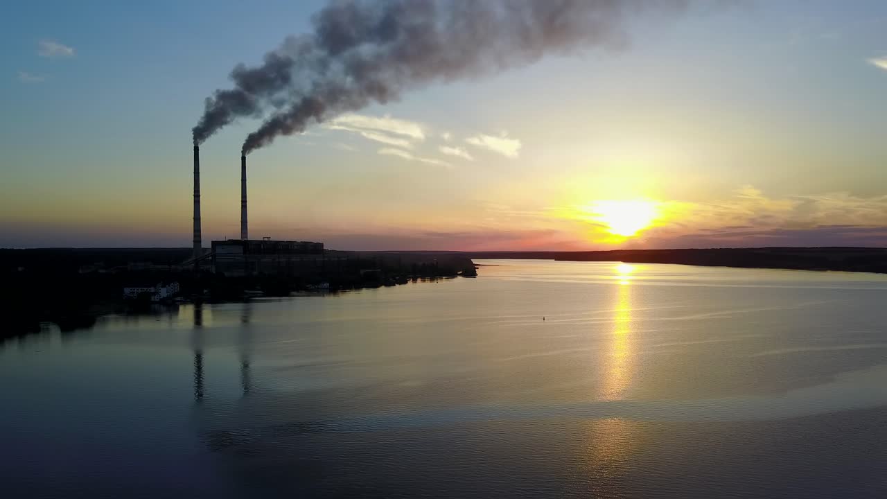 Ciminiera di fabbrica che inquina l'aria. Inquinamento dell'ambiente da parte della fabbrica vicino al fiume sotto il cielo serale.
